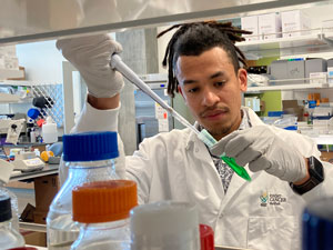 A lab researcher uses a pipette to test for biomarkers.