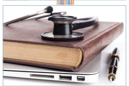 Book and stethoscope sitting on a laptop