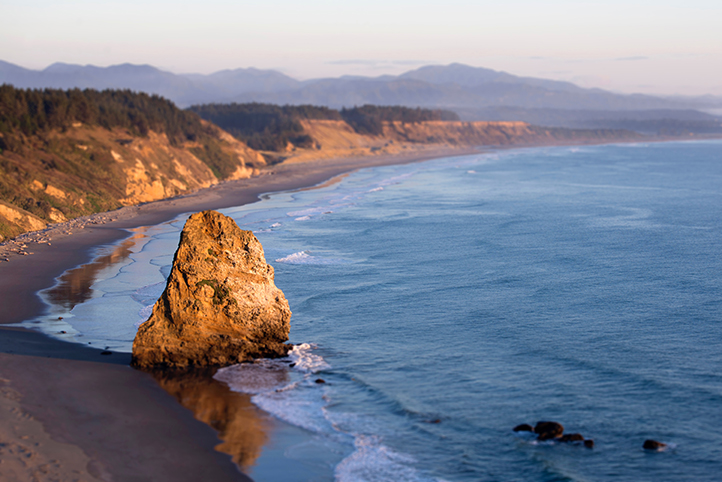 Overview of a beach with a haystack rock off of the South Coast of Oregon at sunrise