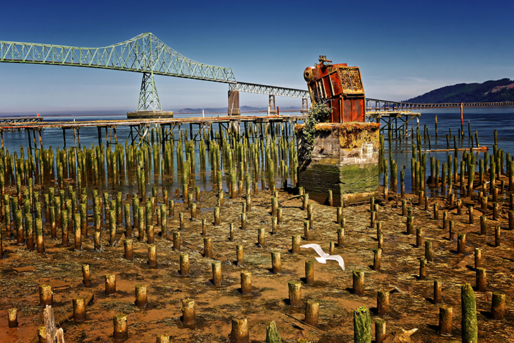 Large bridge and old pylons near the North Coast of Oregon in the midday sun