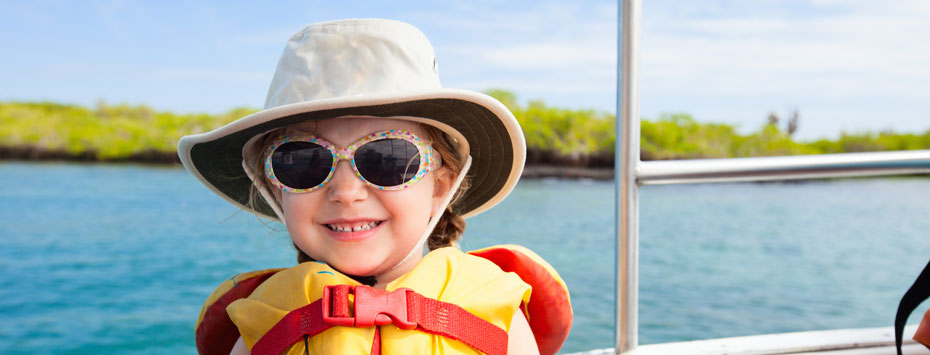 Toddler wearing sunglasses, sun hat, and personal floatation device