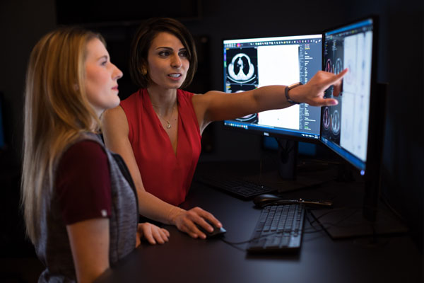 Nuclear Medicine Physician, Nadine Mallak discussing images on a PACS monitor with a colleague.