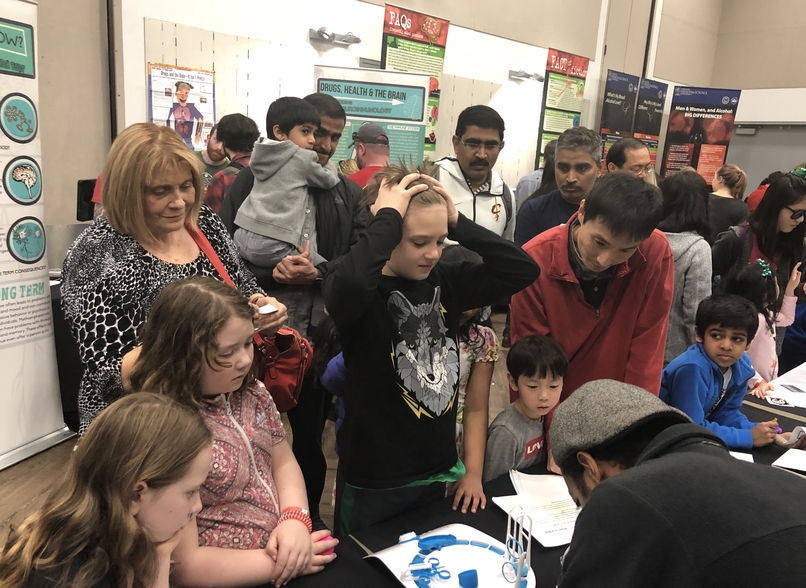 A group of young people watch a neuroscience display.