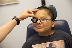Happy boy with glasses having his eyes examined for glaucoma. 