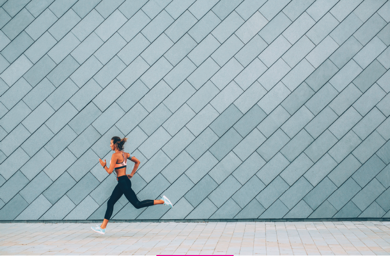 woman runs in front of blue tile wall