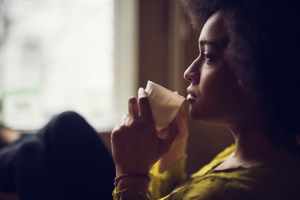 woman sits in front of screen sipping a drink