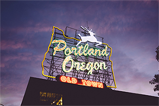 The iconic Oregon-shaped white stag sign at dusk. Text: Portland Oregon Old Town