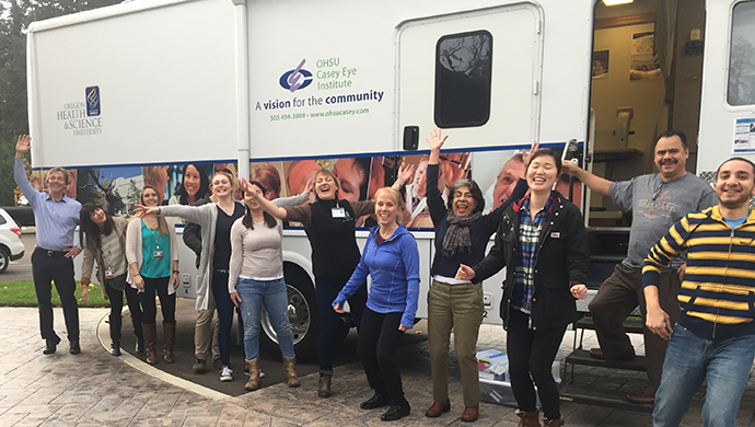Volunteers do a fun pose in front of the mobile clinic.