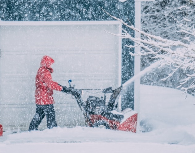 Man using snowplow in front of home