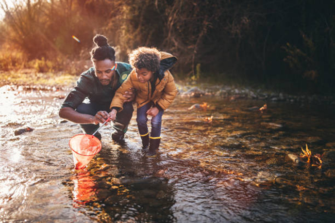 Man with child enjoying net fishing together in a stream