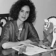 Ileana Contreras Castro sitting at a table with book.