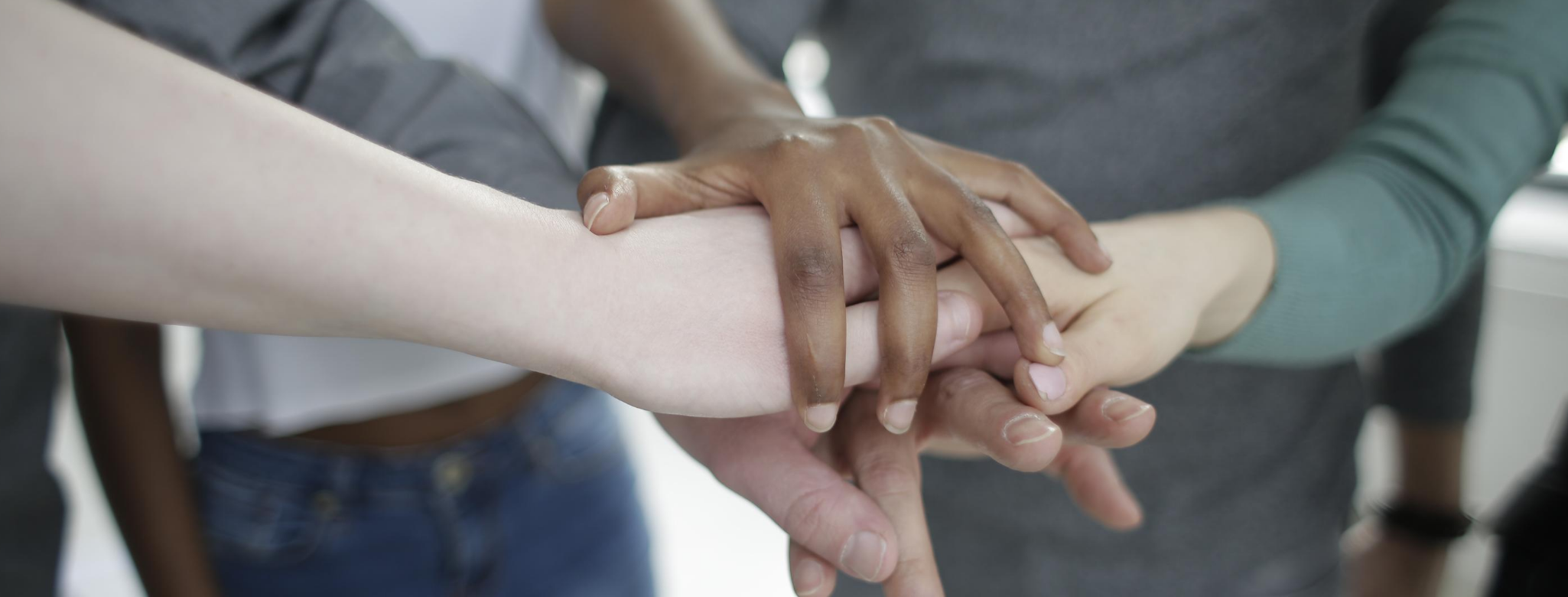 Image of multi-racial hands stacked up in cooperative manner.