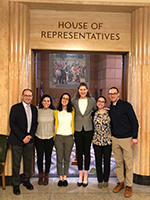 A group of OHSU Pediatric Residents at the Oregon State House posing in a doorway above which reads "House of Representatives."
