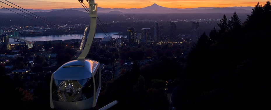 A scenic shot of the OHSU tram arriving at Marquam Hill at sunrise with Mt. Hood in the background.