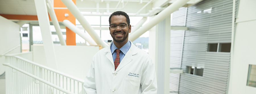 An OHSU provider poses and smiles in the OHSU Skourtes Tower building.
