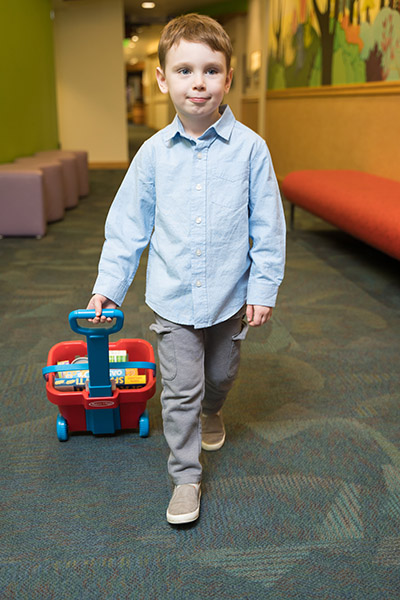 Photo of a boy walking and pulling a small wagon in a hallway at OHSU Doernbecher Children's Hospital.