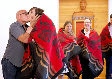 Mike Lewis kisses his daughter, Kyna Lewis, during a blanket ceremony at the Wy’east Post Baccalaureate Pathway graduation ceremony in June 2019.