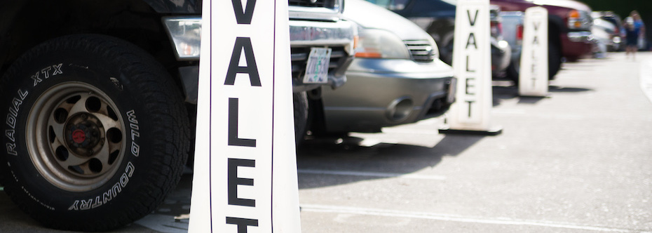 Photo of valet signs in a parking lot with cars parked.