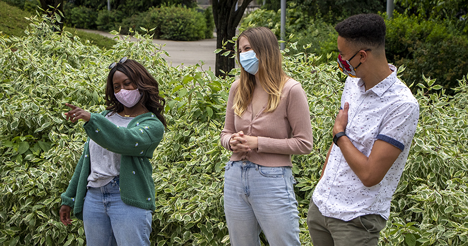 Three postbac students in garden wearing surgical masks