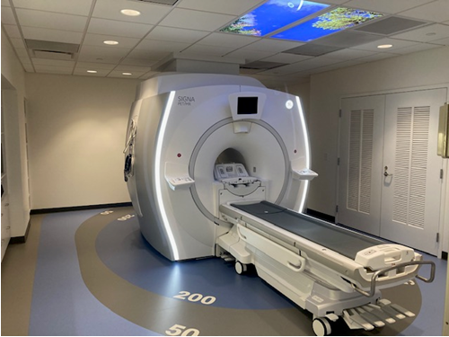 The PET/MRI scanner is a large boxy machine with a patient table in front of it.