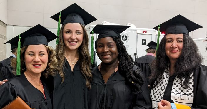 Four DoM Graduates Standing in Their Regalia