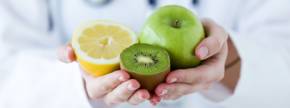 A health care provider holds a lemon, a kiwi and an apple.