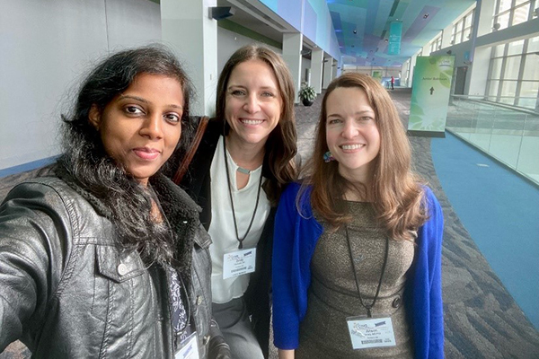 A photo of three women taking a selfie in a conference lobby.