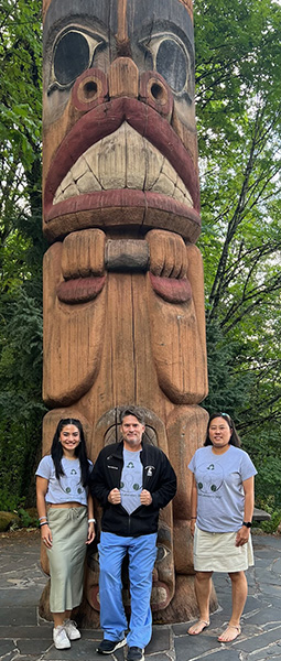 Morgan lab personnel standing next to totem sculpture