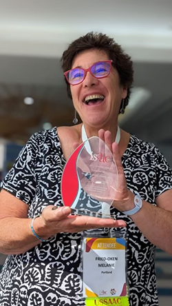 Dr. Melanie Fried-Oken holding an award she was given at the ISAAC Conference in Cancun, Mexico.