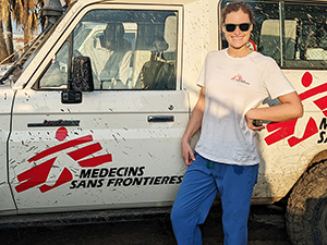 An OHSU alum stands in front of a white truck with the logo of Doctors Without Borders