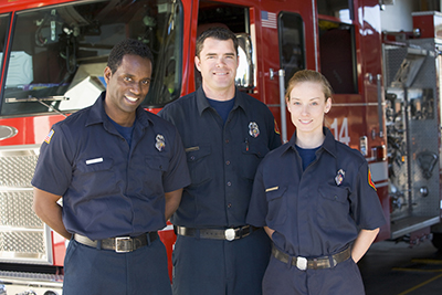 Three firefighters standing by a fire engine