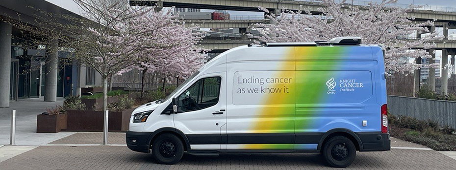 The Mobile Outreach van, which is white, yellow, green and blue and wrapped with text reading "Ending cancer as we know it" and "OHSU Knight Cancer Institute."