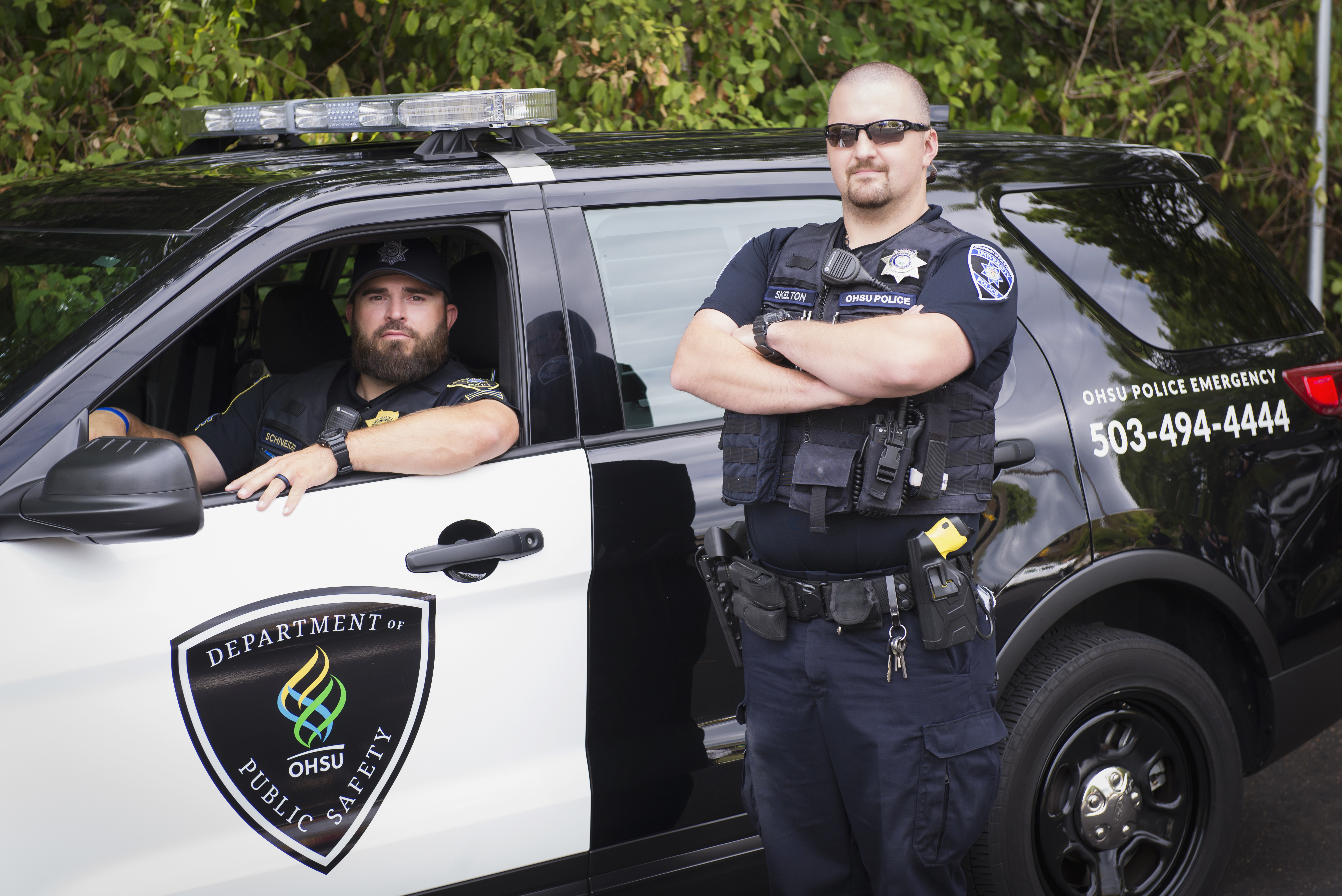 Officer in police vehicle and office standing next to vehicle