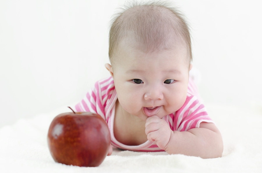 Tiny Asian girl reaching for an apple