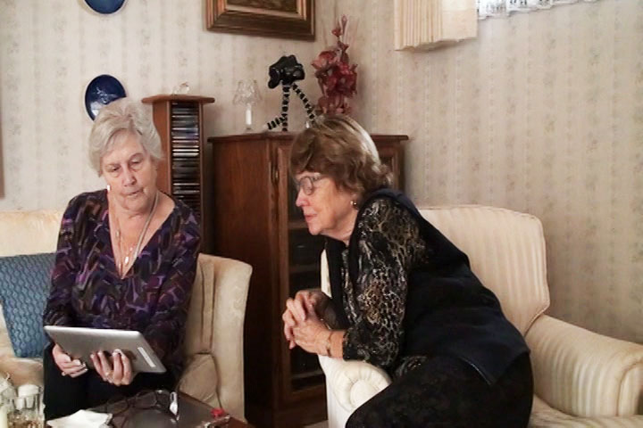 Two women sitting in a living room and looking at an iPad