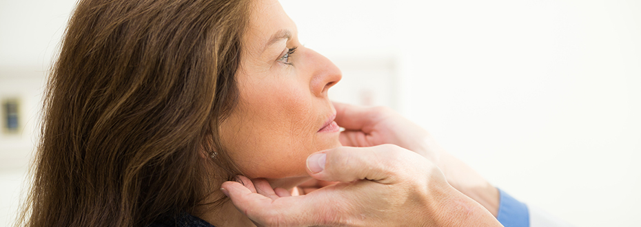 Dr. Reid gently examining a patient's thyroid gland by touching the neck area.