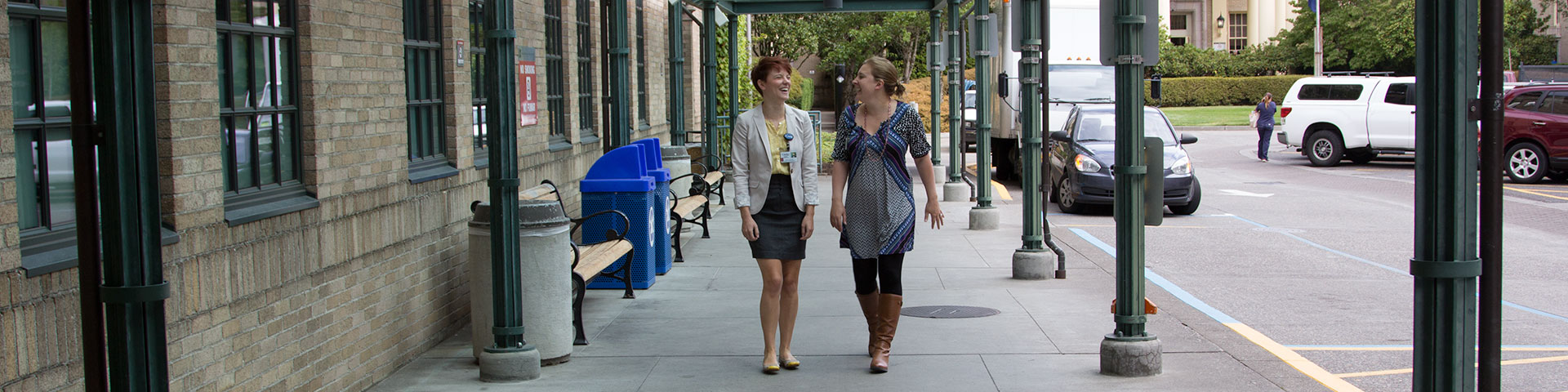 Two women walking and talking outside on campus
