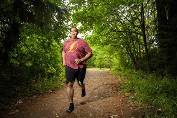 Dorrian Rhodes running along a trail in a forest