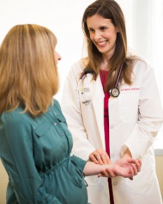 An OHSU cardiology specialist takes the pulse of a seated patient