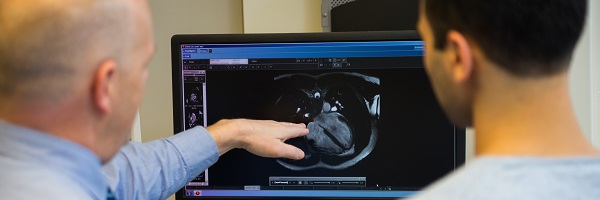 An OHSU cardiac specialist points to an image on a computer screen in an exam room