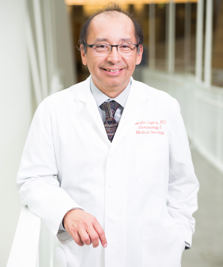 Dr. Charles Lopez in white coat, smiling