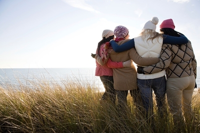 Four women embracing each other at the coast