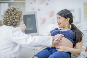 Woman receiving ultrasound scan by obgyn