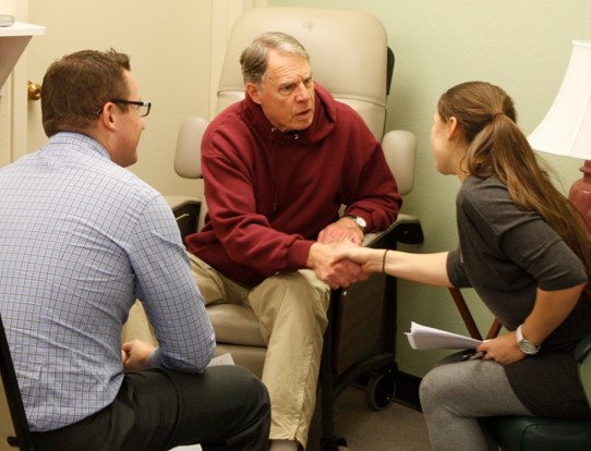 Younger students shaking hands with senior patient