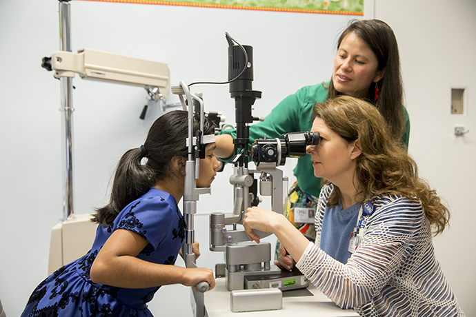 Young girl receiving eye exam from doctor and nurse