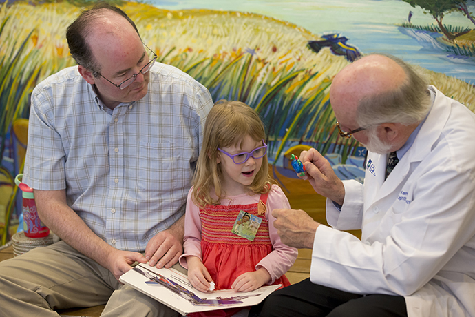 Dr. Karr with a young female patient and her father