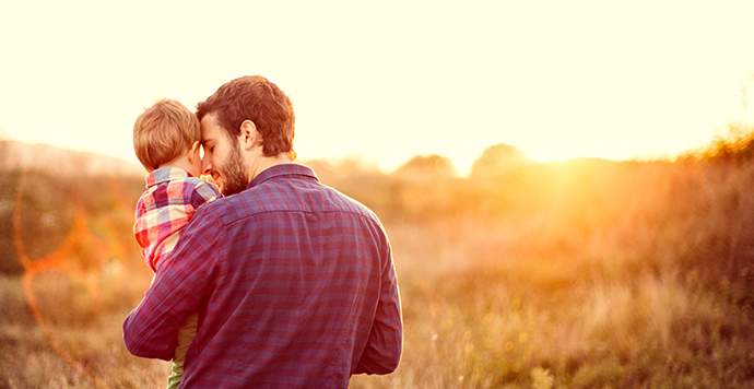 Father holding son at sunset