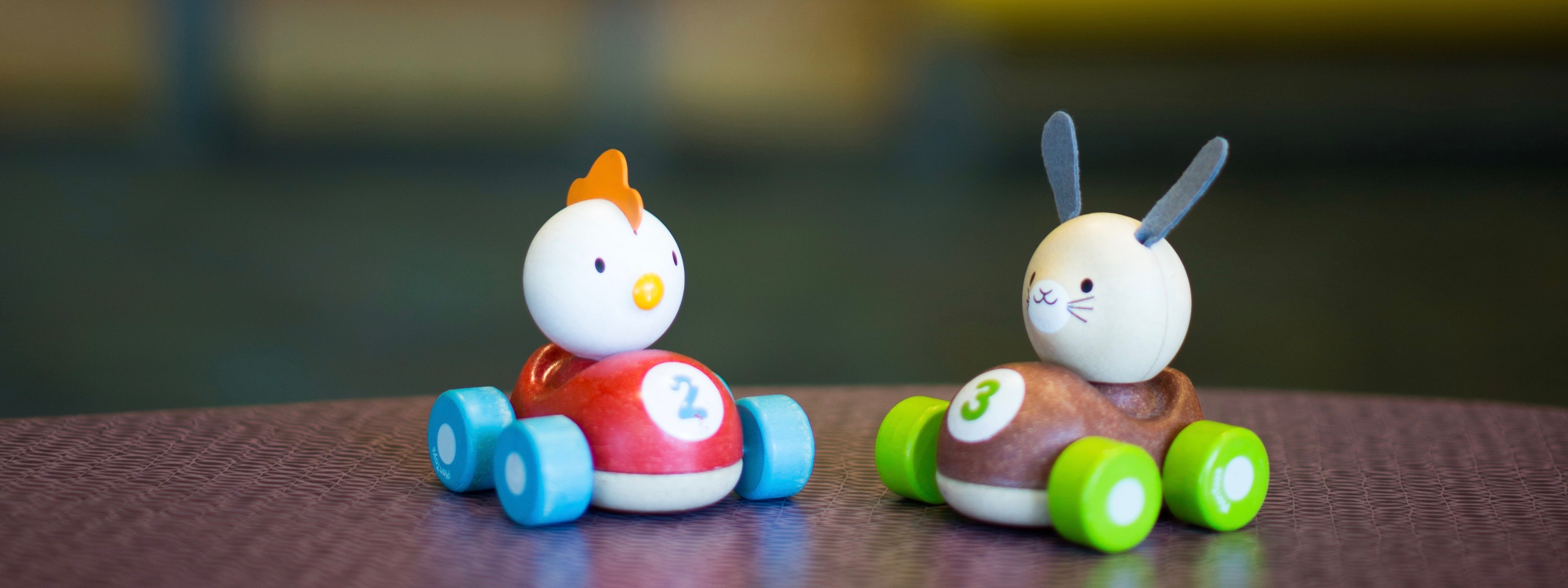Photo of two toy cars with the numbers two and three on them being driven by a chicken and a bunny