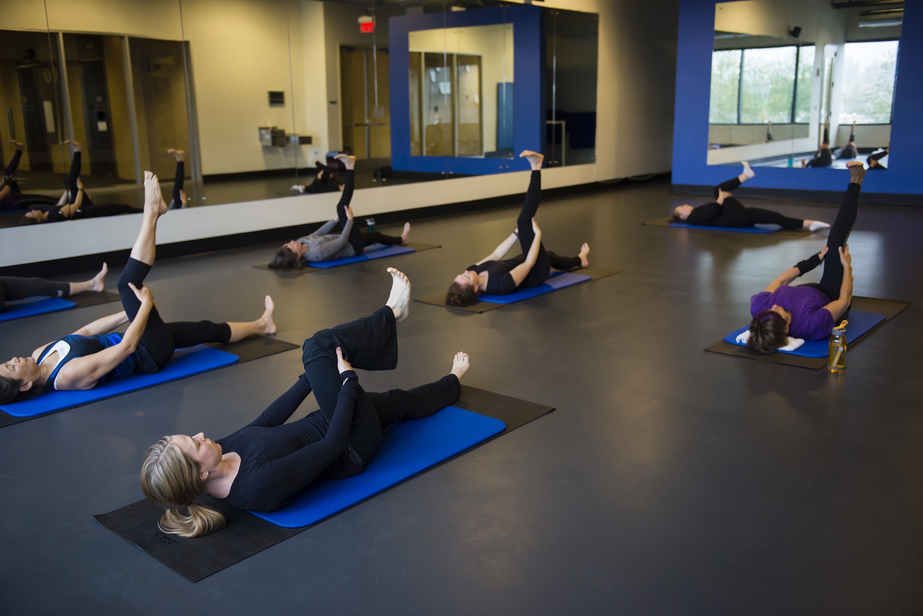 Pilates participants on mats performing floor exercises.