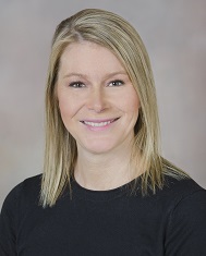 Headshot of a smiling woman with shoulder-length blond hair wearing a black shirt